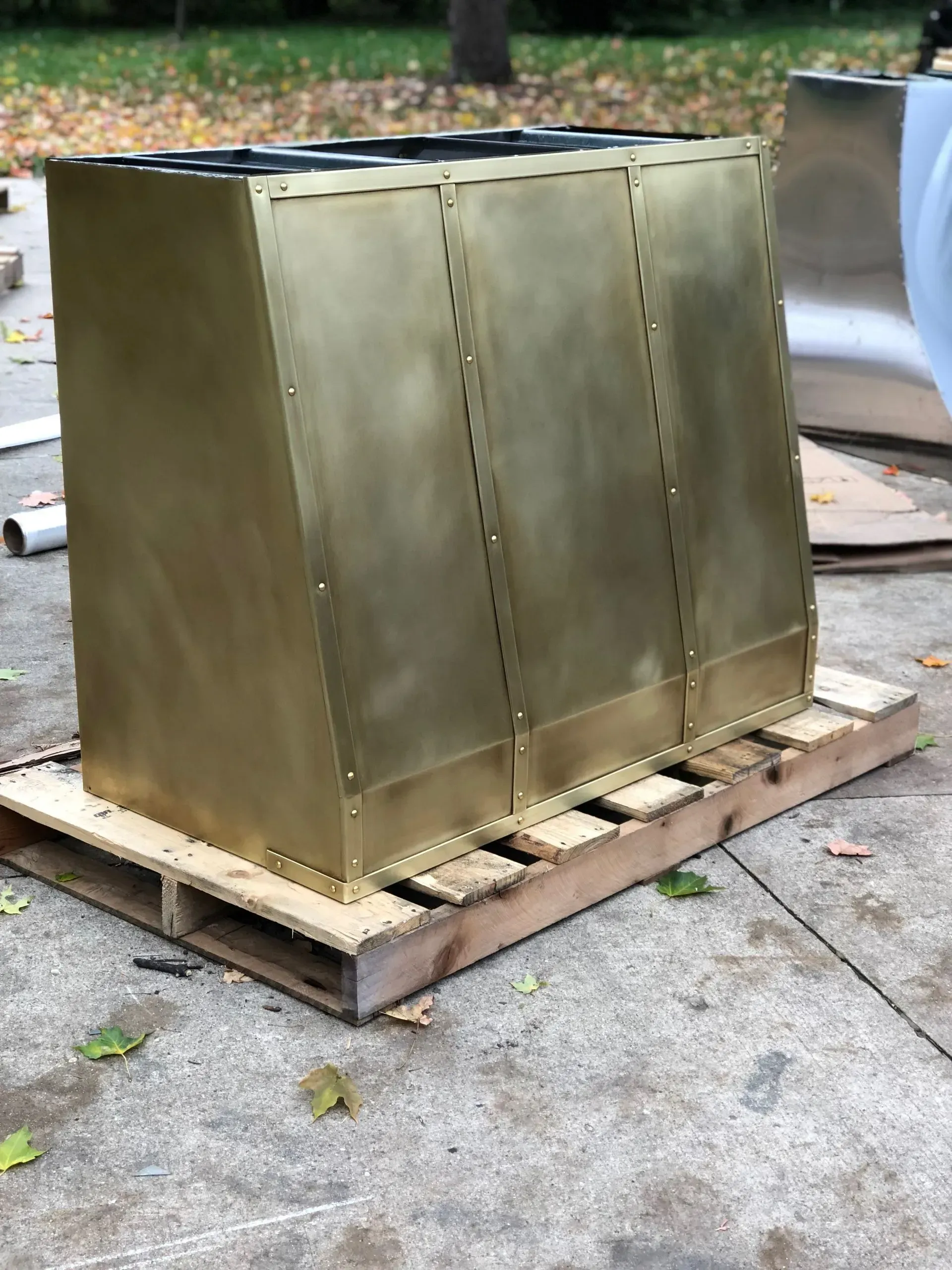 A brass box is sitting on top of a wooden pallet.