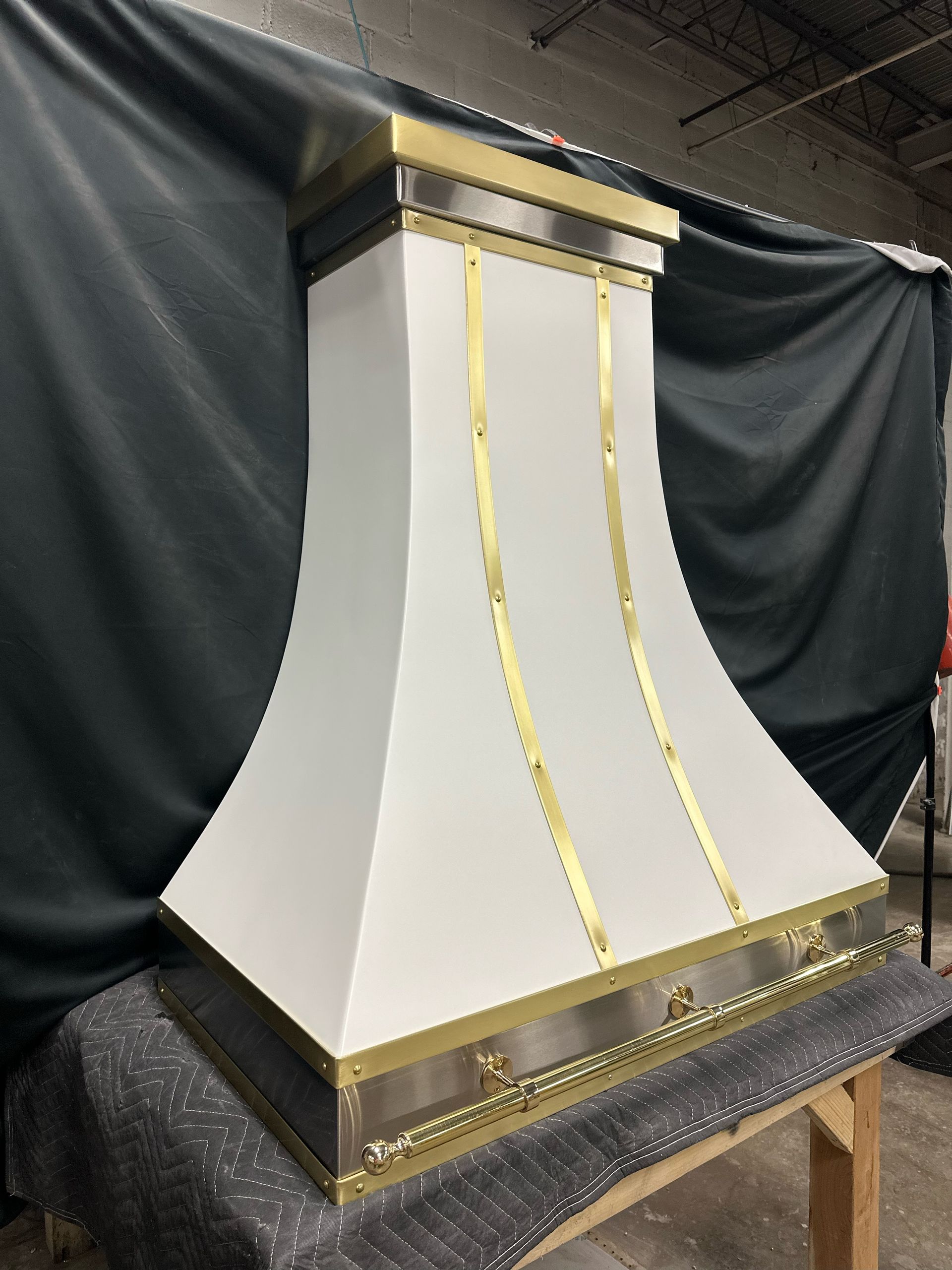 A white and gold hood is sitting on top of a wooden table.