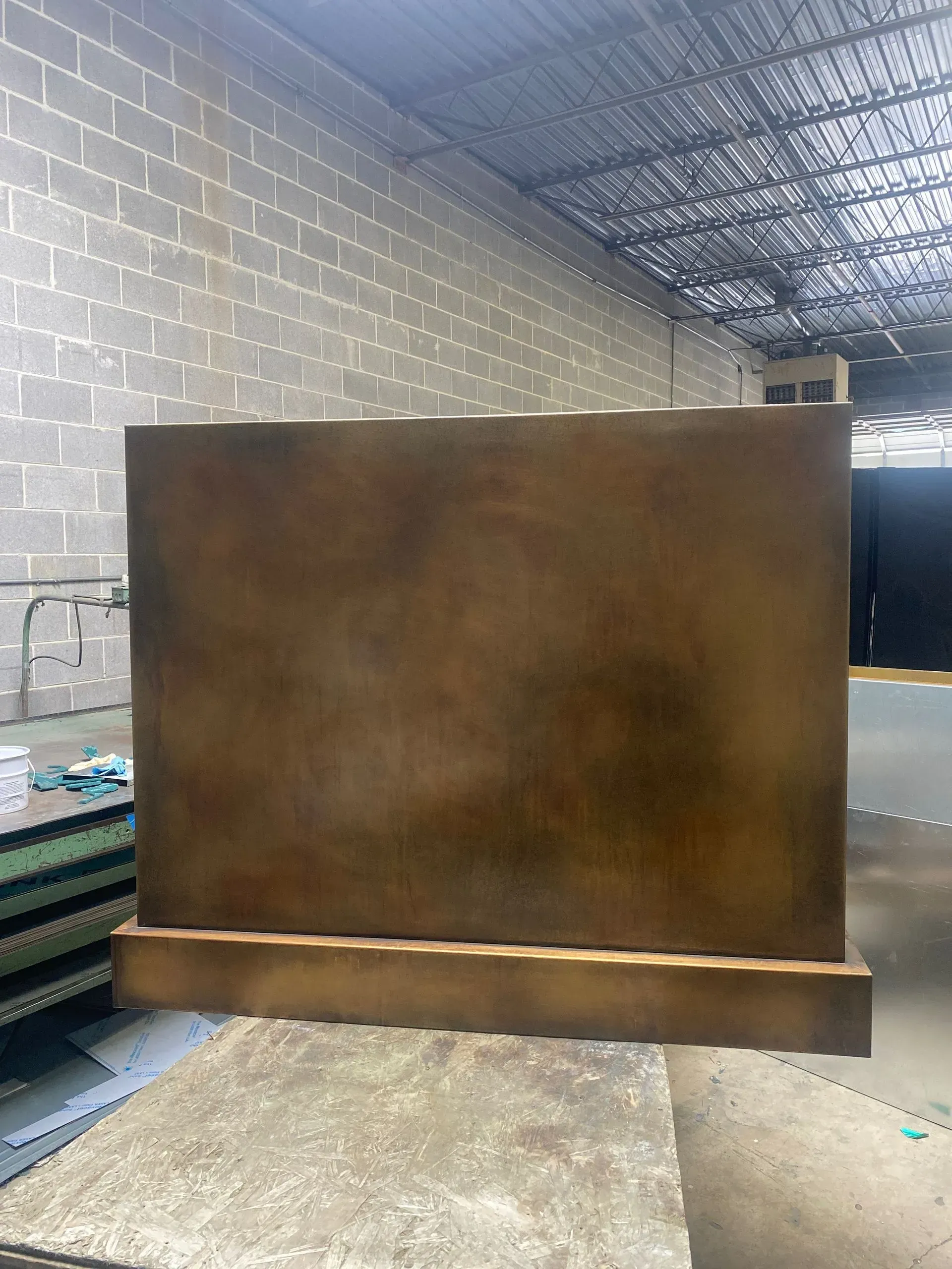 A large piece of wood is sitting on top of a wooden table in a warehouse.