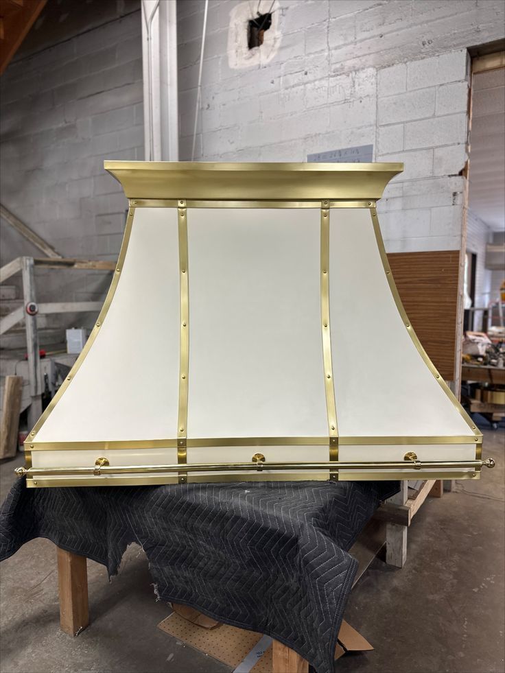 A white and gold hood is sitting on top of a wooden table.