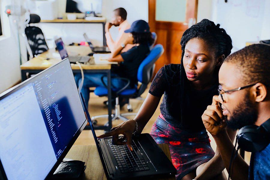 A man and a woman are looking at a laptop computer.