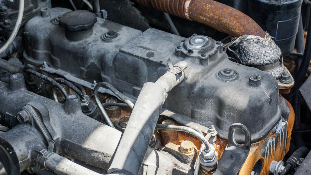 Dirty engine compartment with rusted parts and hoses, showing signs of wear and oil buildup.