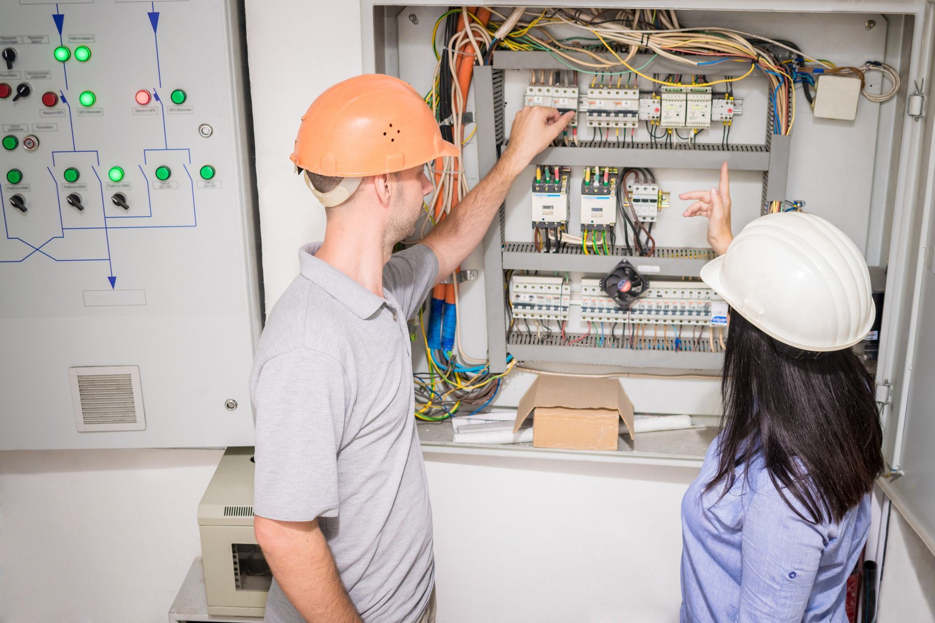 Two people in hard hats inspecting electrical panel Two people in hard hats inspecting electrical panel