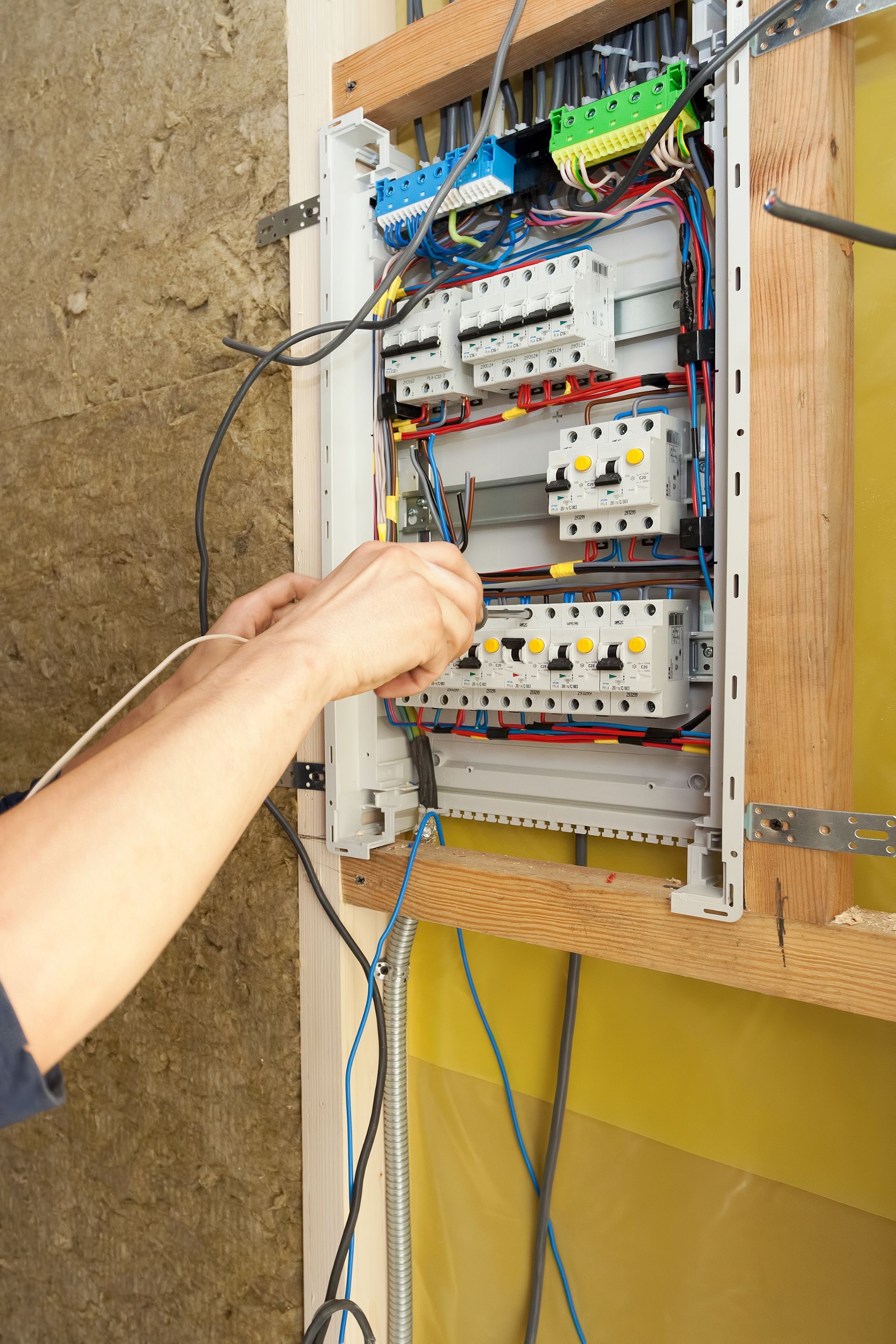Electrician working on an electrical panel mounted on a wooden frame
