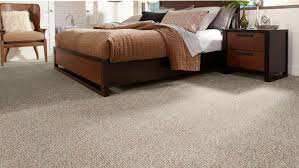 A bedroom with a bed , nightstand , chair and carpet.
