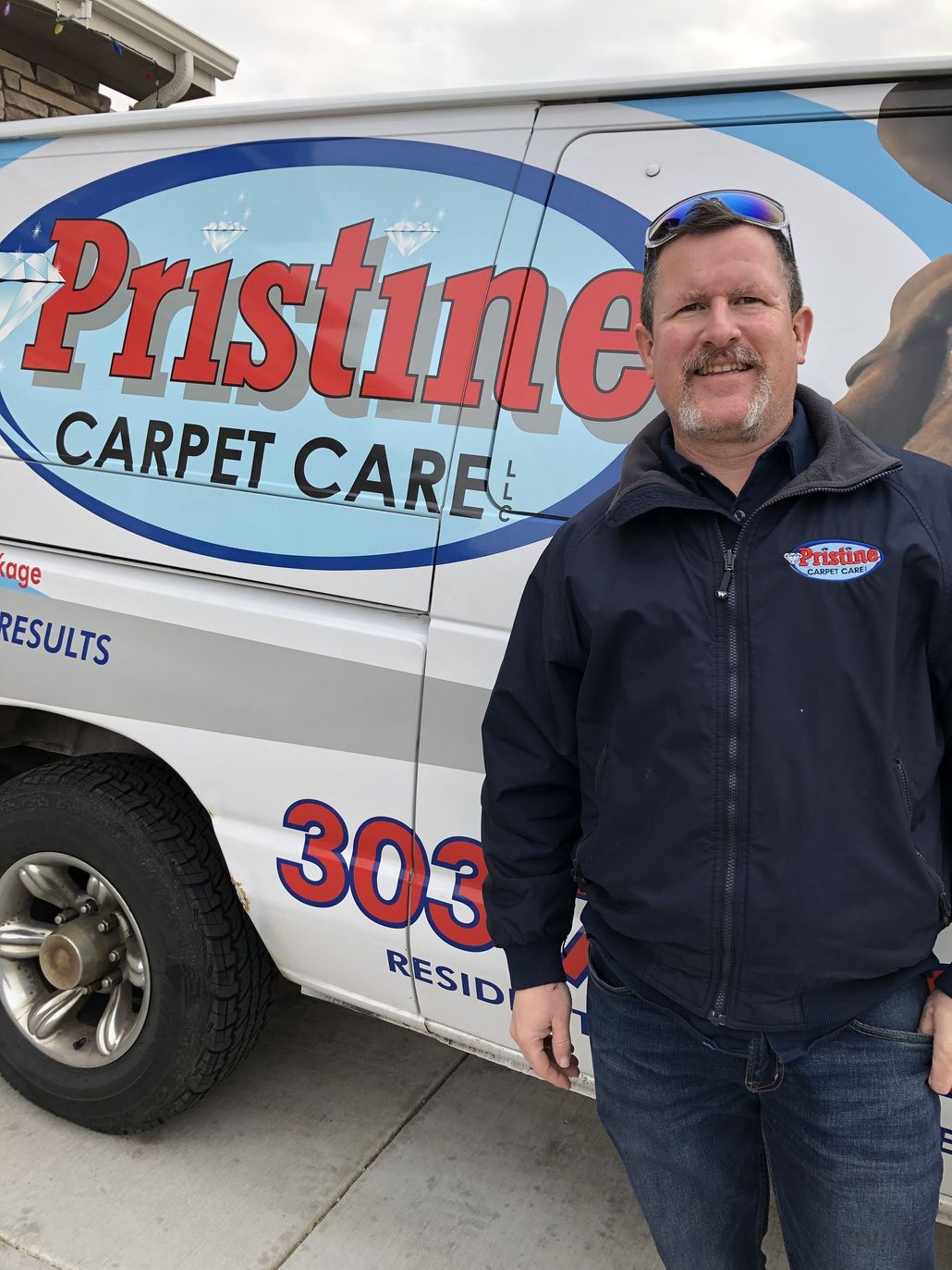 A man is standing in front of a pristine carpet care van A man is standing in front of a pristine carpet care van