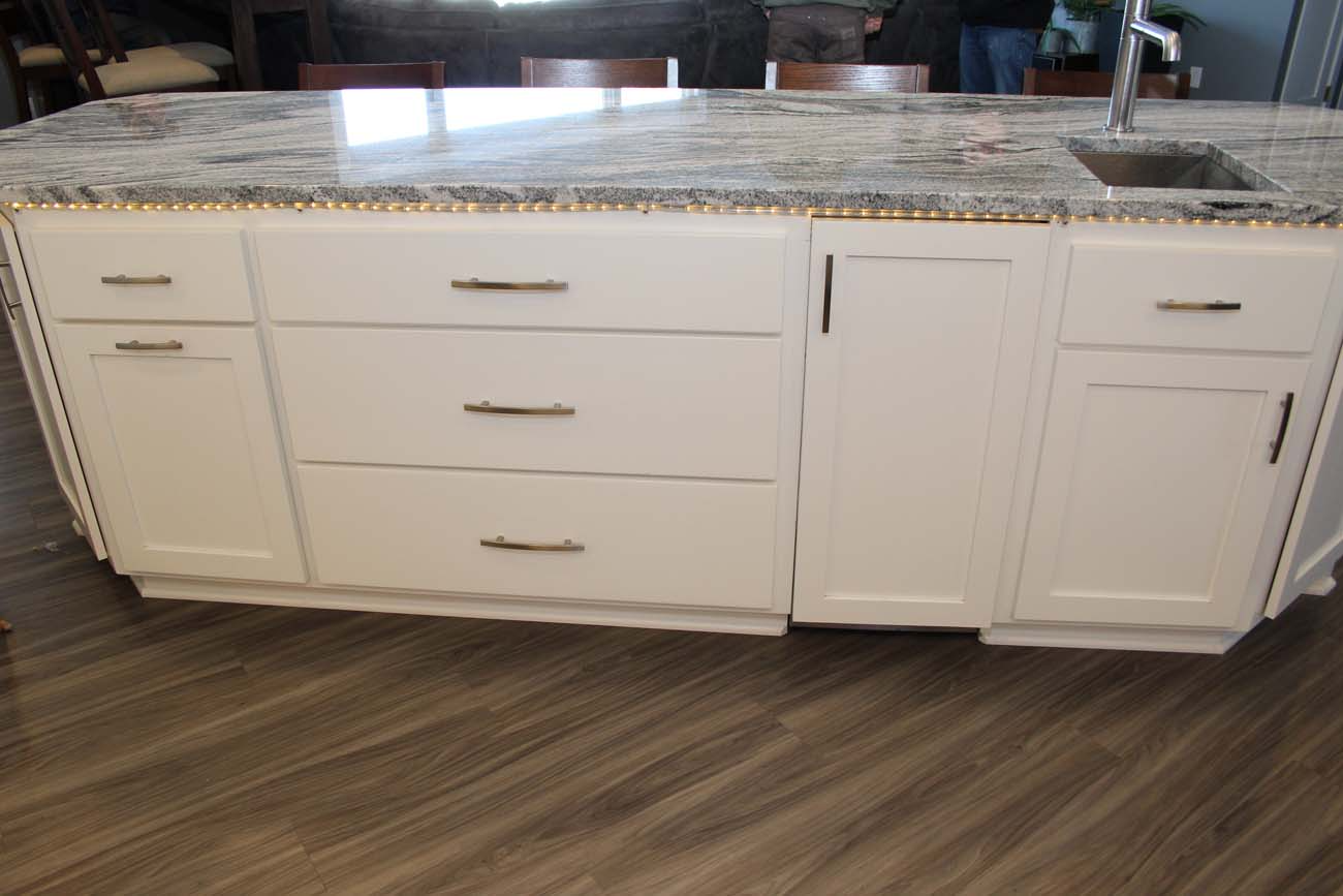A kitchen island with white cabinets and a granite counter top.
