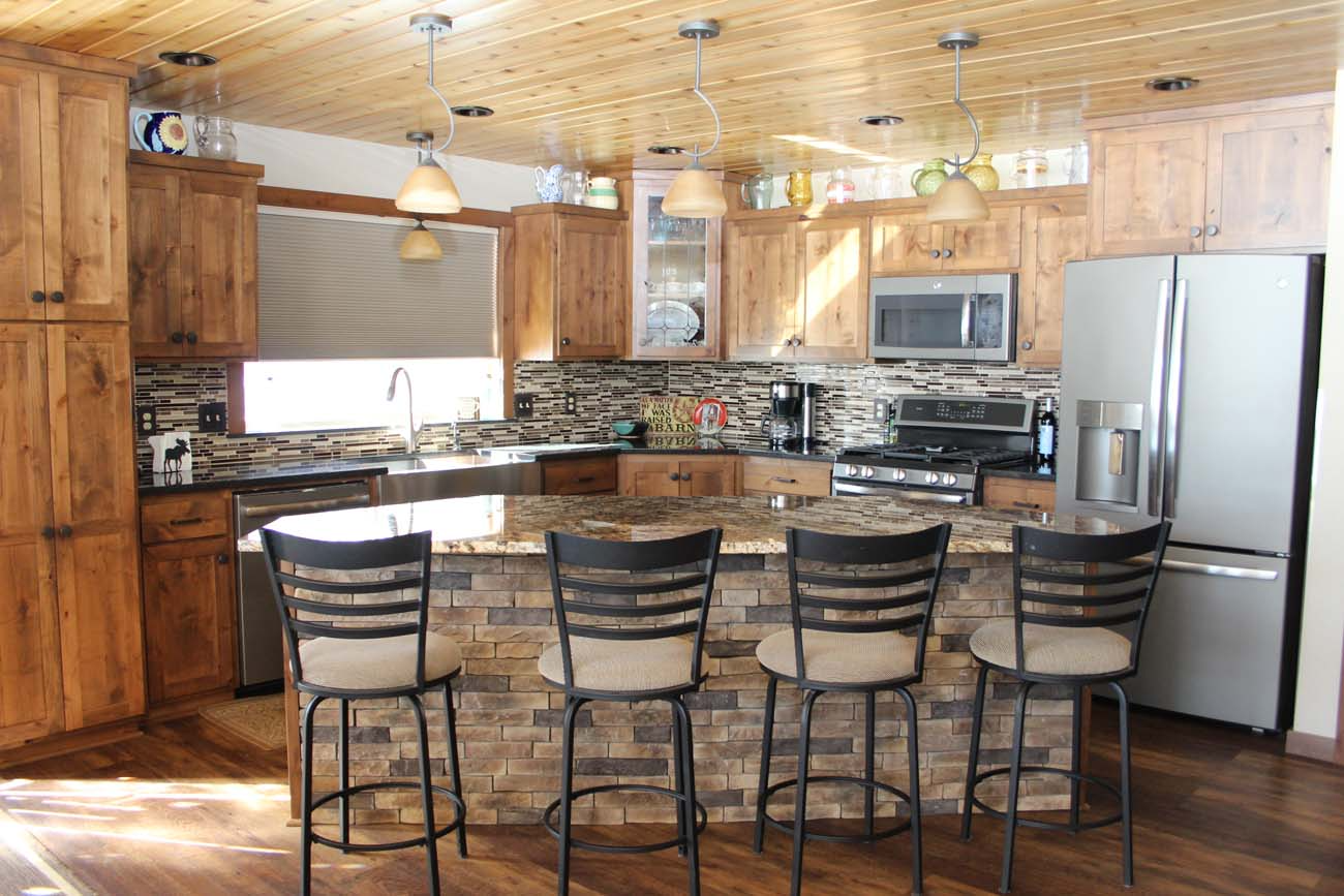 A kitchen with wooden cabinets , granite counter tops , stainless steel appliances and a large island.