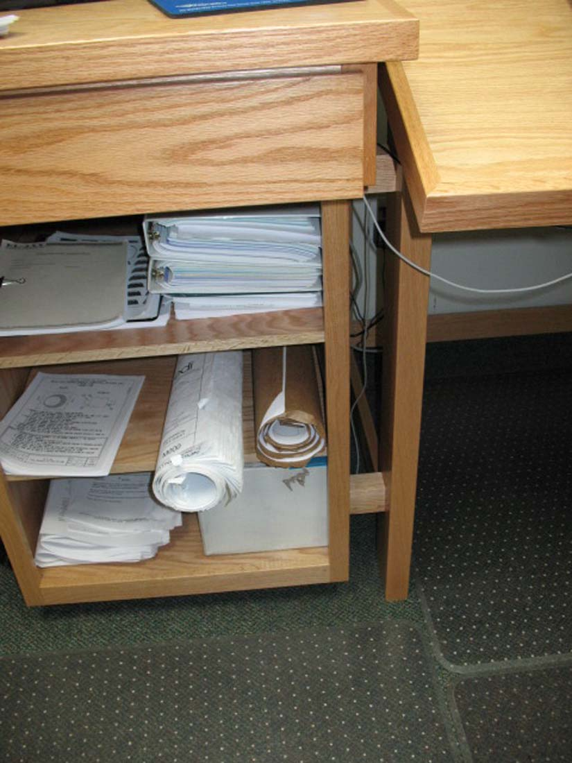 A wooden desk with a stack of papers on it