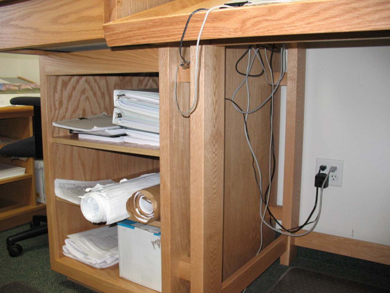 A wooden desk with a bunch of papers on it