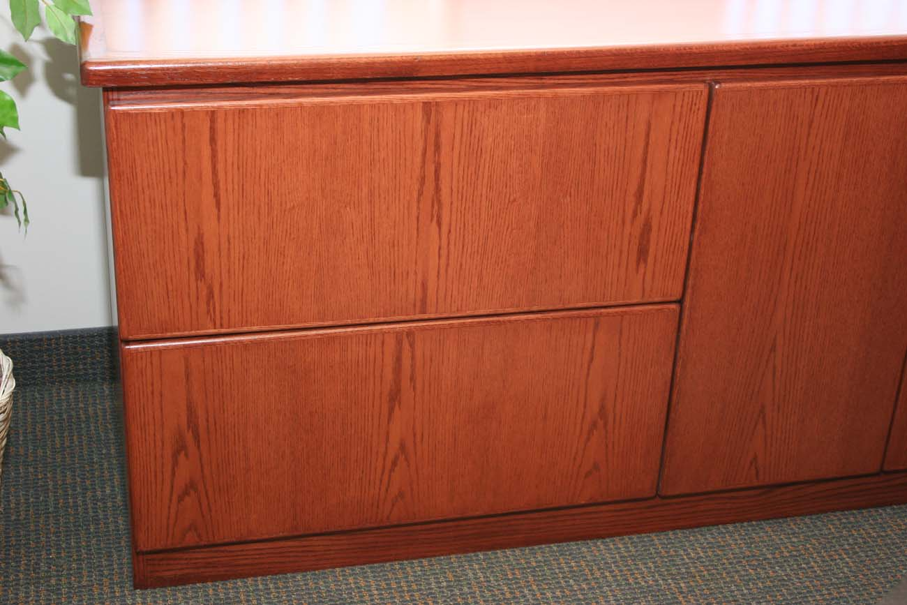 A wooden cabinet with drawers and a plant in the background.
