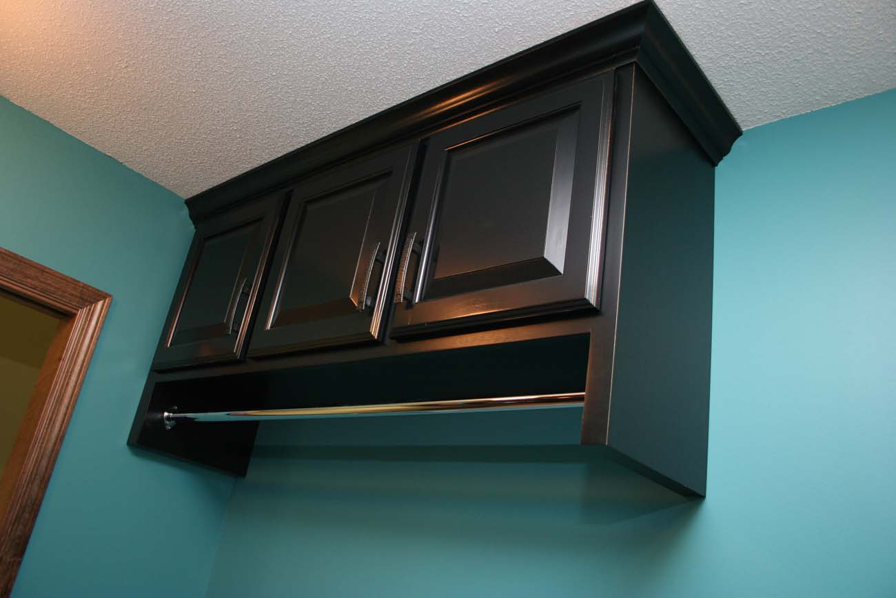 A black cabinet is hanging from the ceiling in a room with blue walls