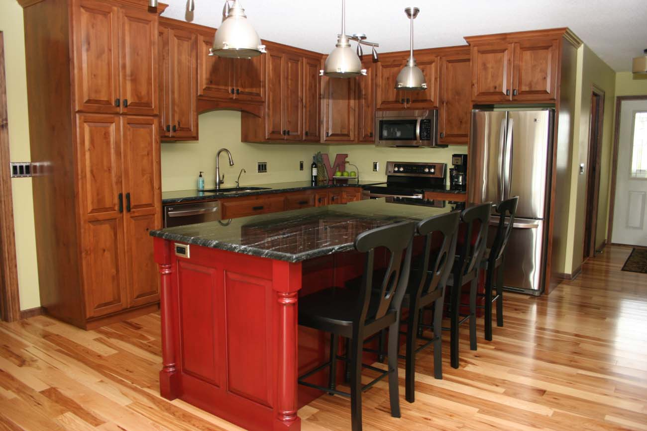 A kitchen with a red island and black chairs