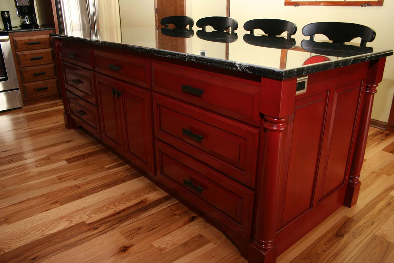 A kitchen with red cabinets and black granite counter tops