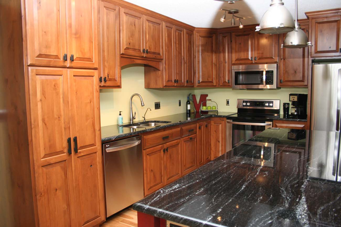 A kitchen with wooden cabinets and black granite counter tops
