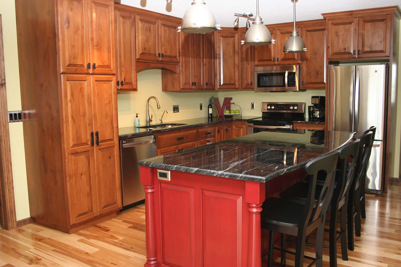 A kitchen with wooden cabinets and a large red island