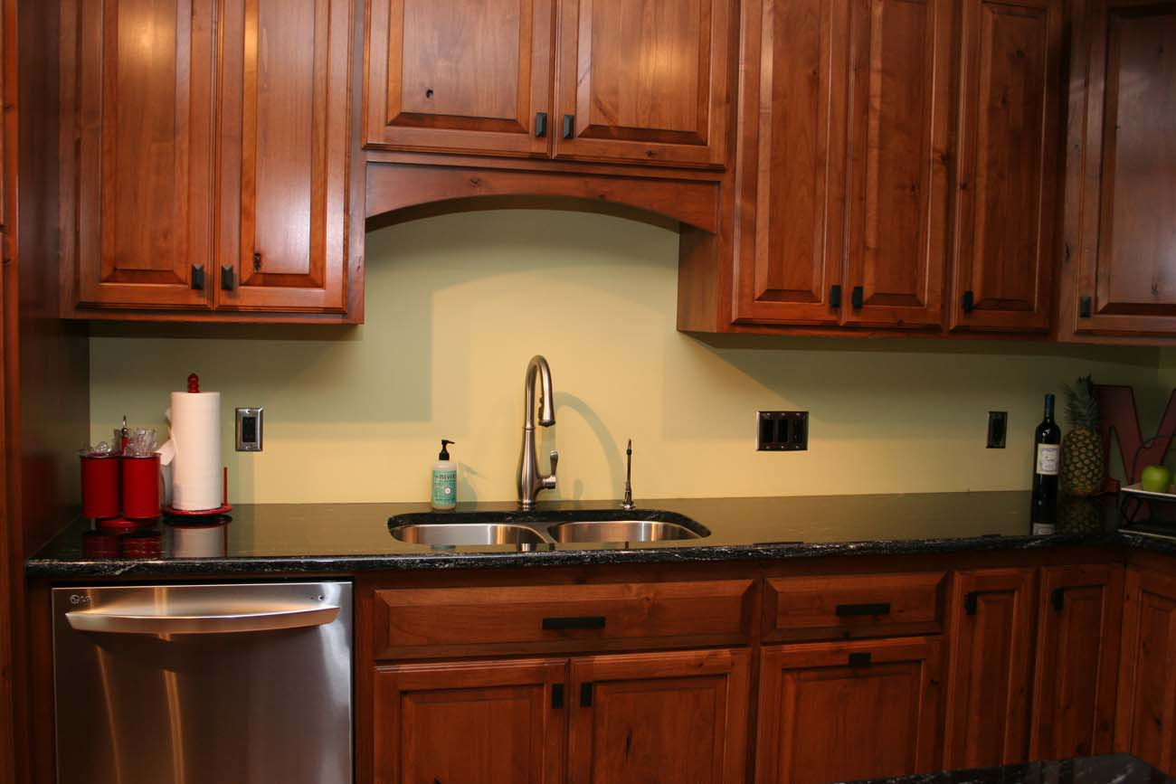 A kitchen with wooden cabinets and a stainless steel dishwasher