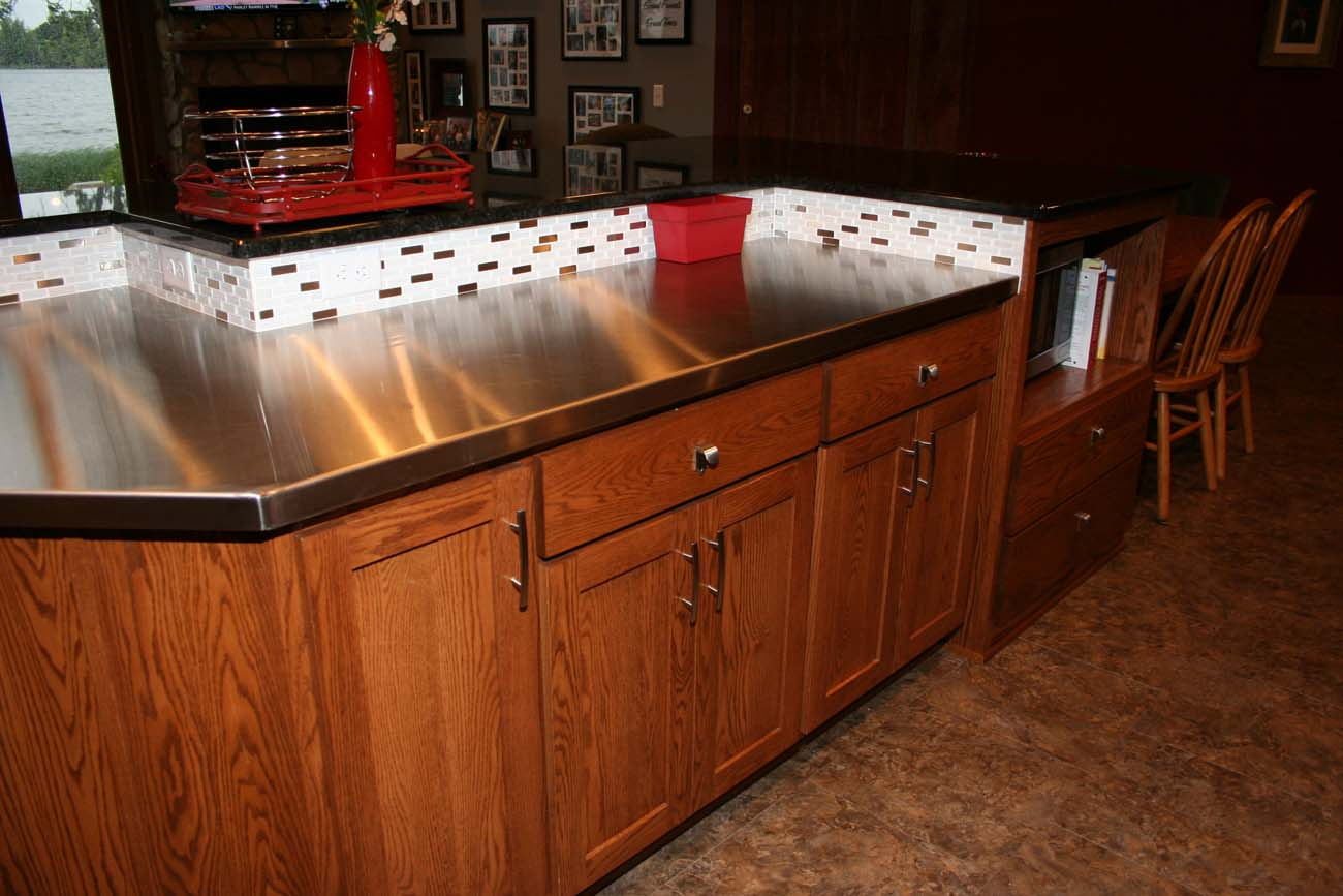 A kitchen with wooden cabinets and a stainless steel counter top.