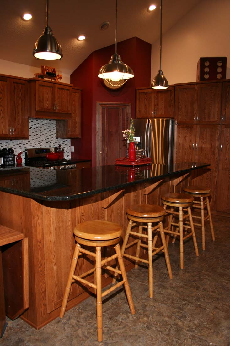 A kitchen with a black counter top and wooden stools