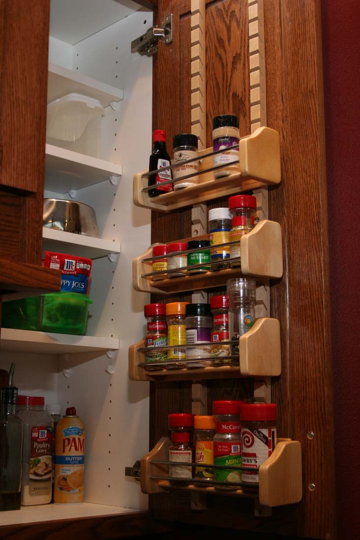 A spice rack is hanging from the side of a cabinet.