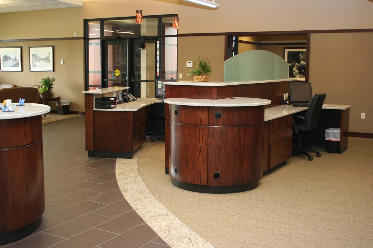 A bank lobby with a wooden counter and a computer desk