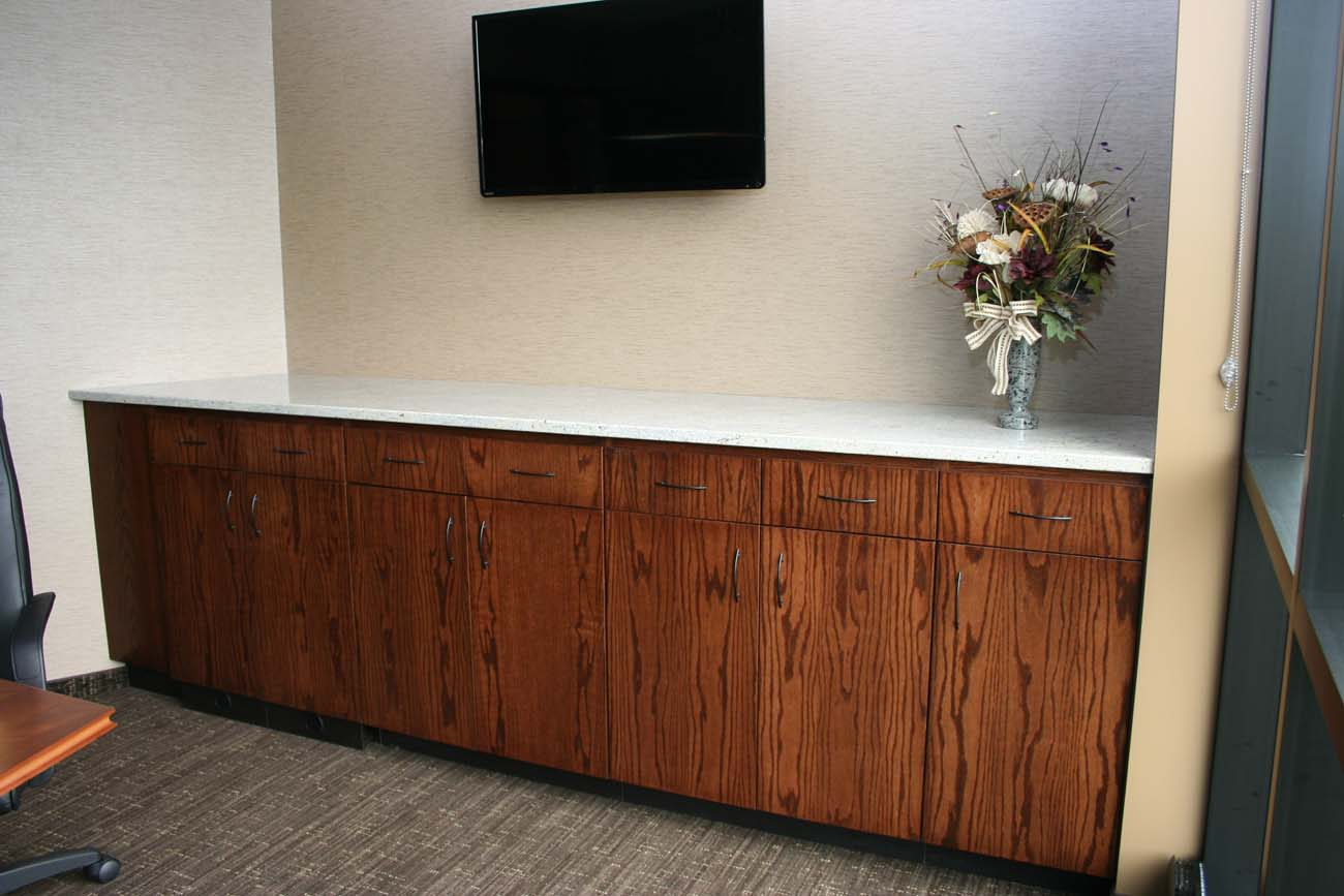 A vase of flowers sits on a counter next to a flat screen tv