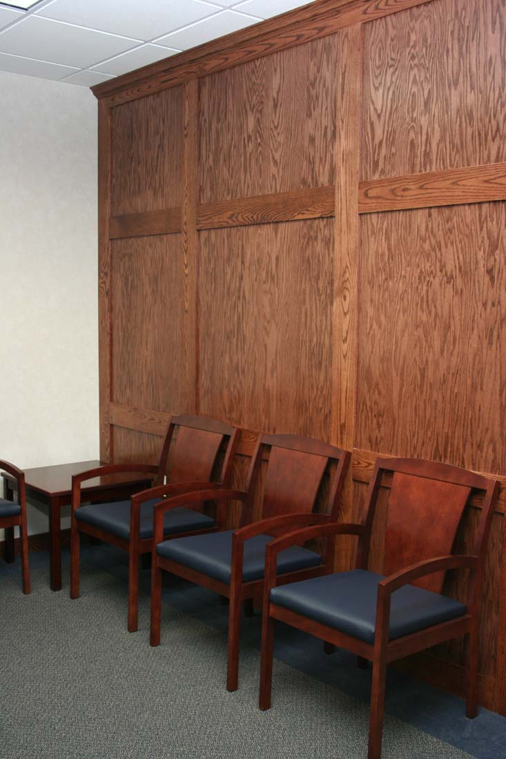 A row of chairs in a waiting room with wood paneling