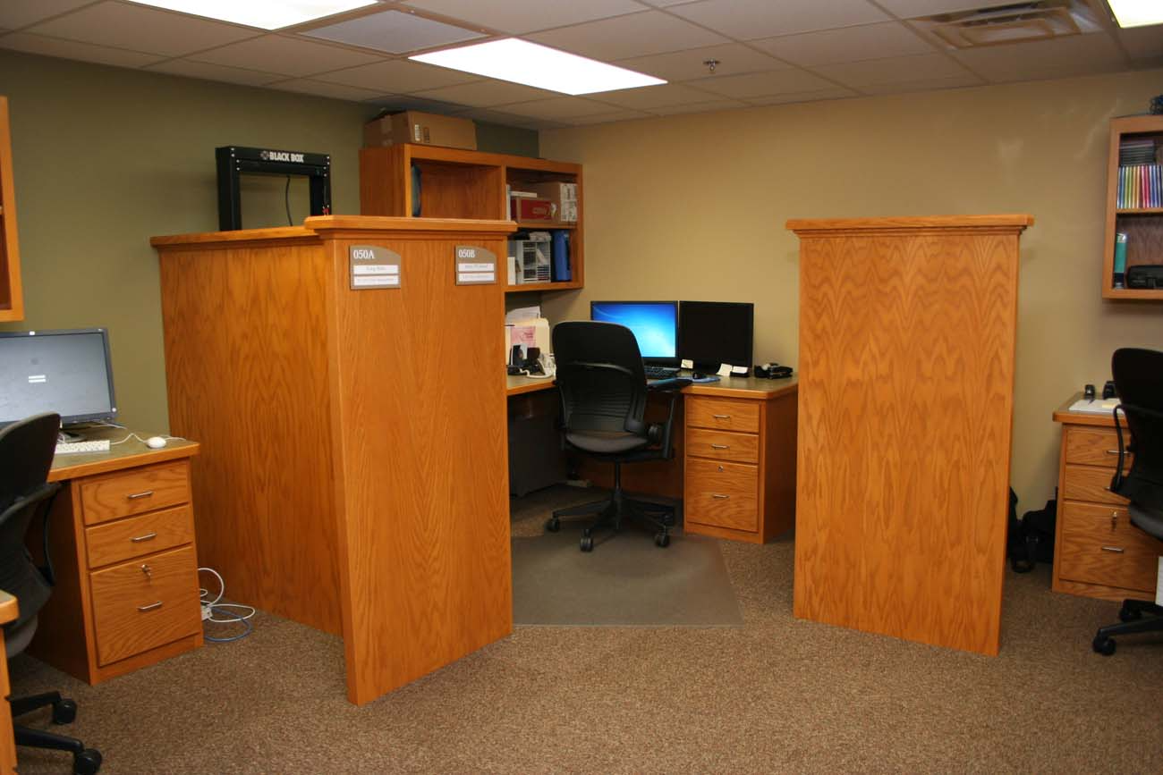 A cubicle in an office with a computer on the desk