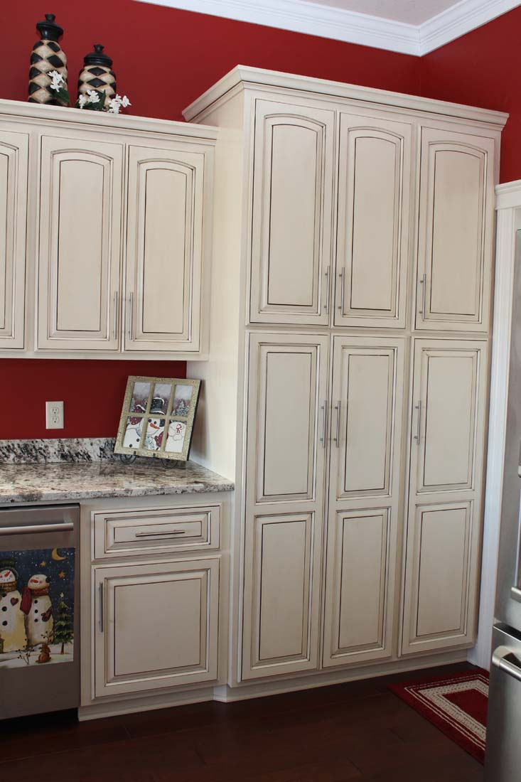 A kitchen with white cabinets and red walls
