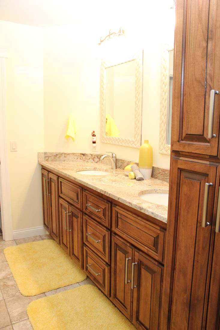 A bathroom with two sinks , two mirrors , and wooden cabinets.