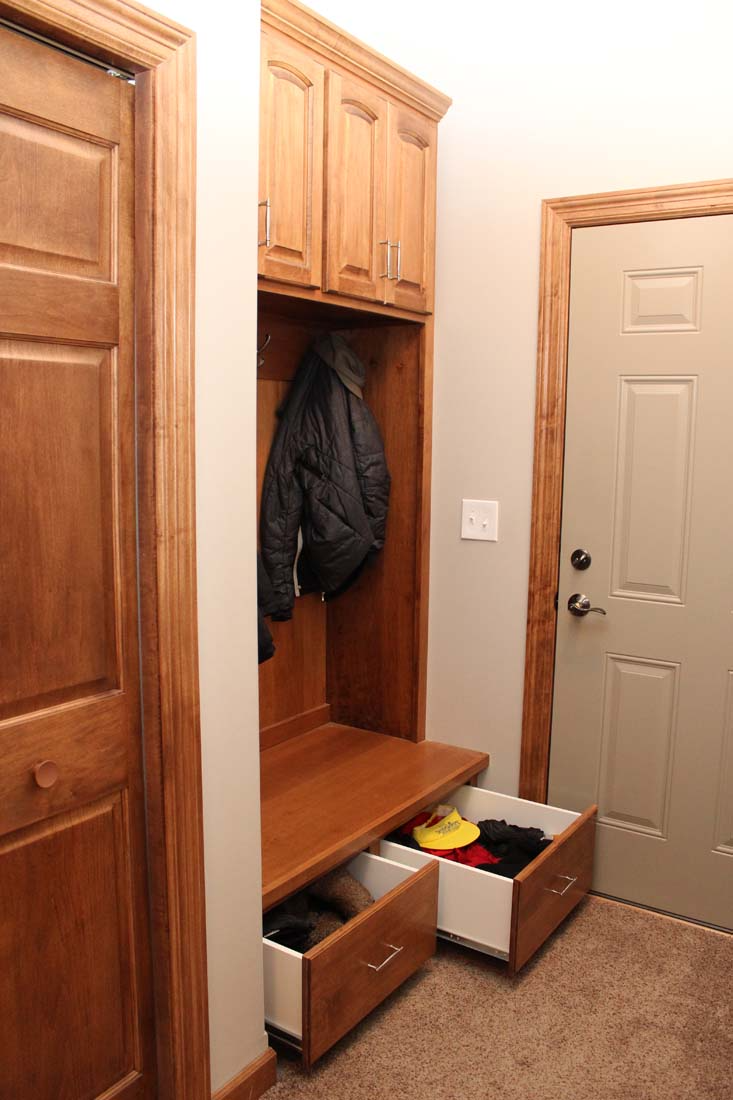 A hallway with wooden cabinets and drawers and a door