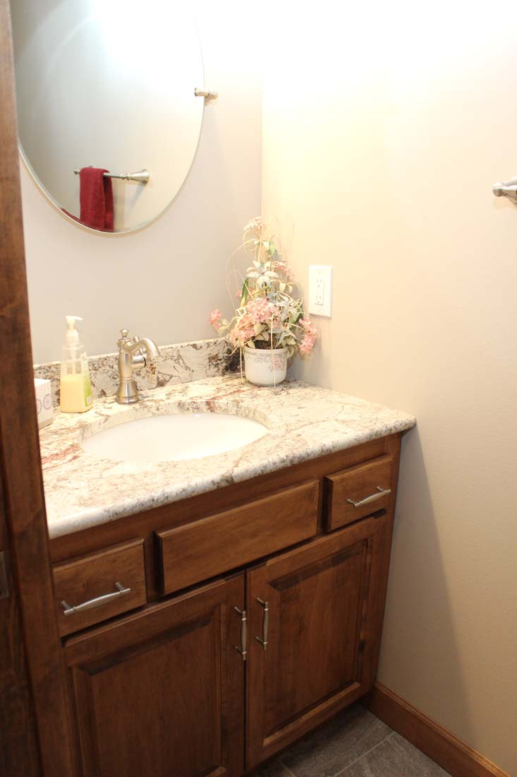 A bathroom with a sink , mirror , and wooden cabinets.