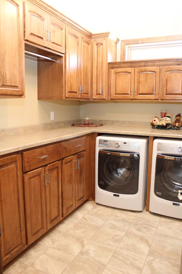 A laundry room with a washer and dryer and wooden cabinets.