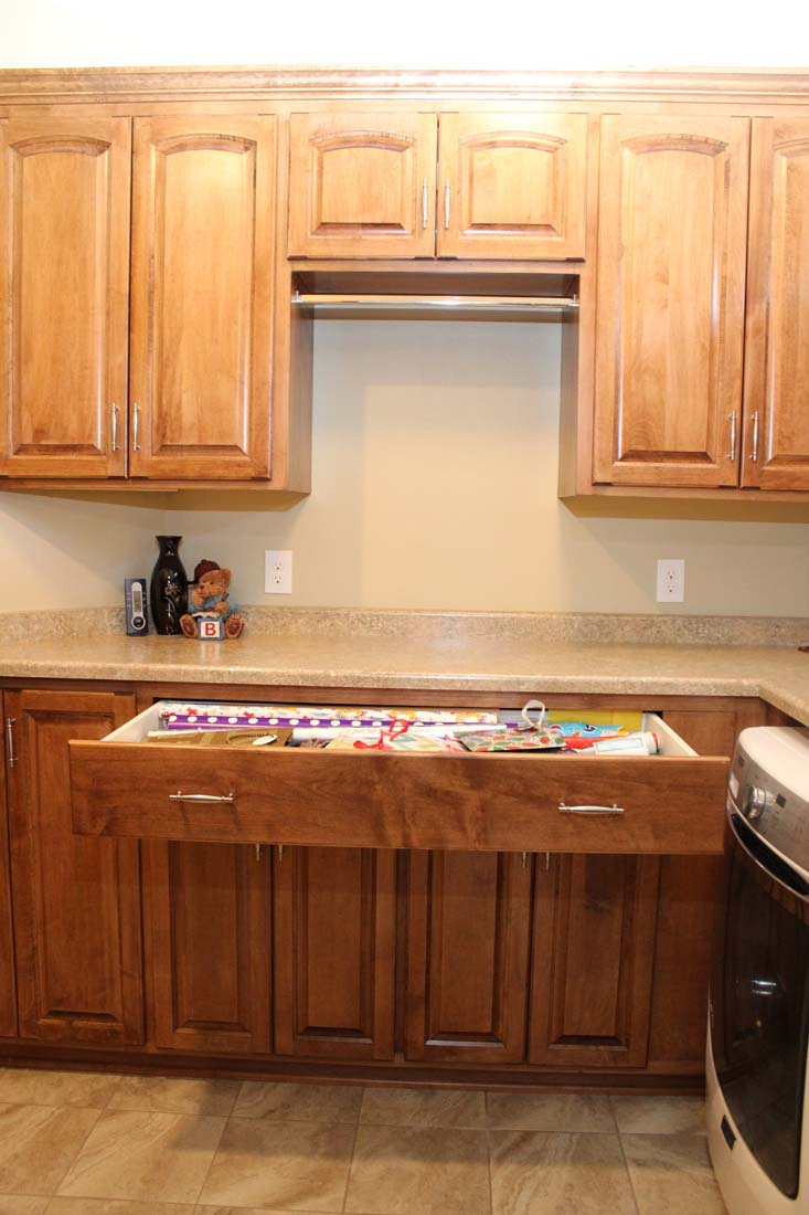 A kitchen with wooden cabinets and a drawer open.