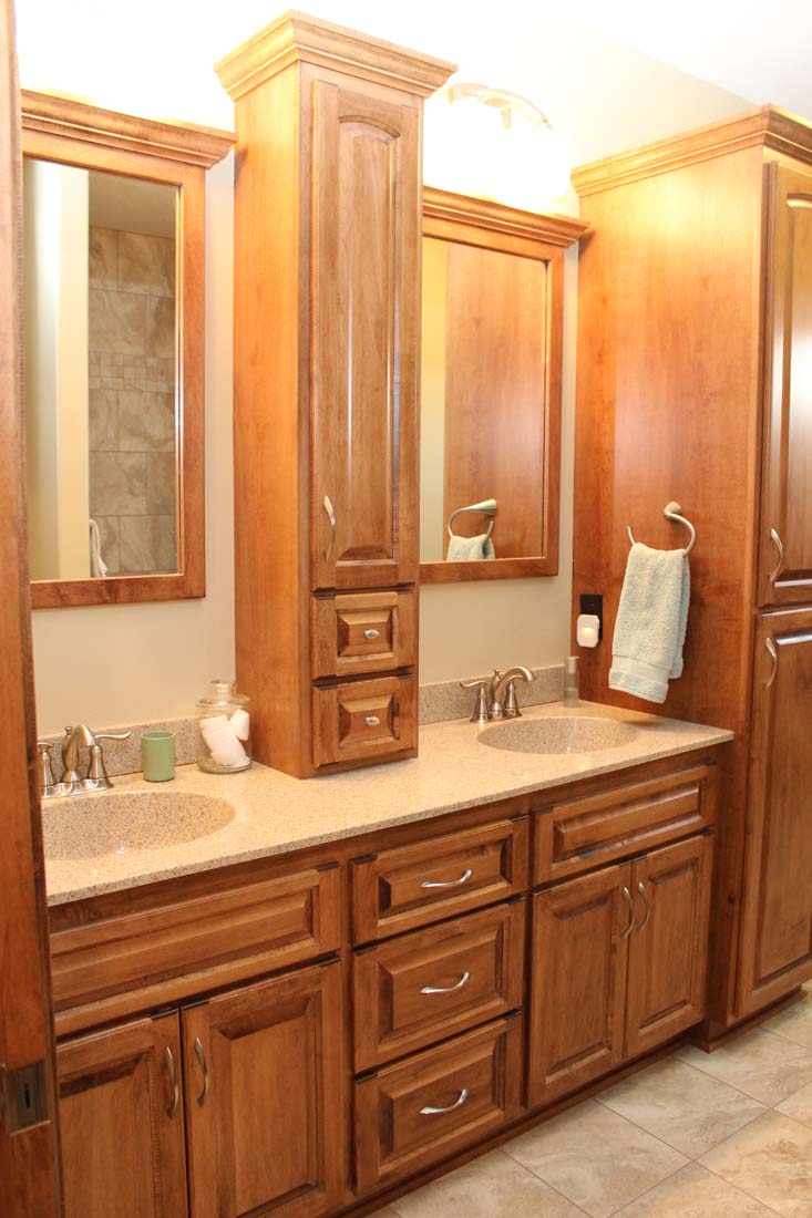 A bathroom with two sinks , two mirrors , and wooden cabinets.