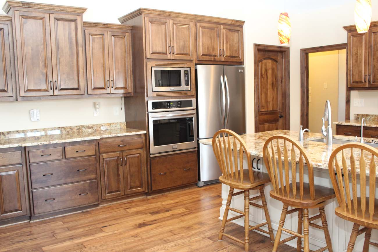 A kitchen with wooden cabinets , granite counter tops , stainless steel appliances and a large island.
