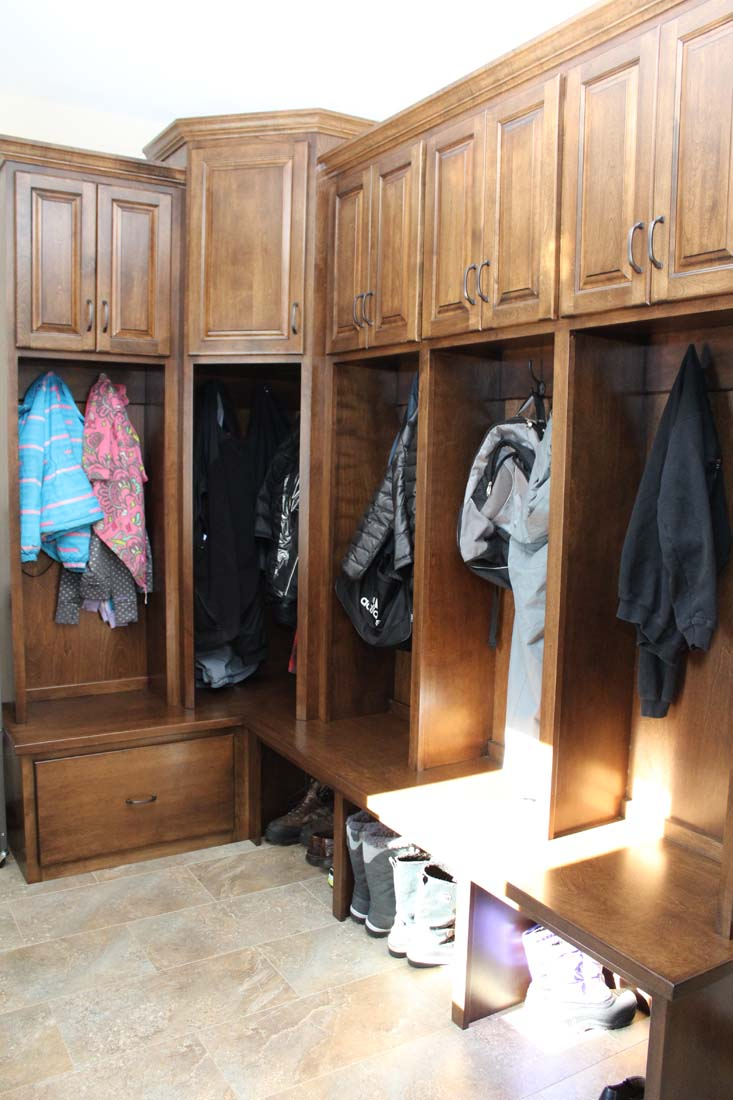 A closet with wooden cabinets and jackets hanging on the wall