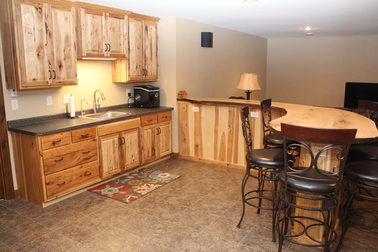 A kitchen with wooden cabinets , a sink , and a bar.