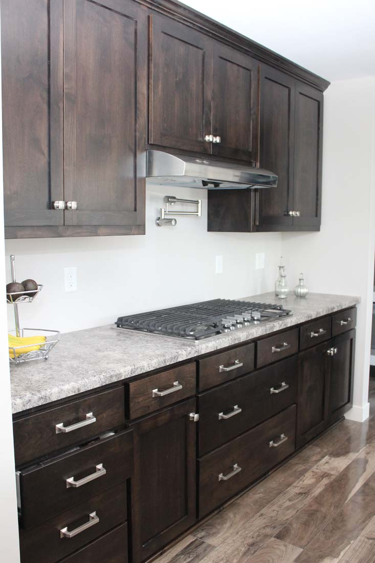 A kitchen with wooden cabinets , granite counter tops , and a stove top oven.