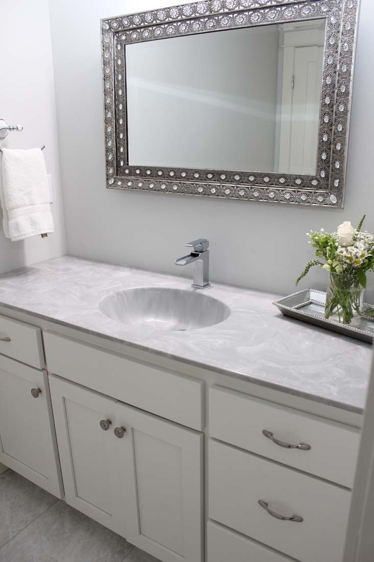 A bathroom with a sink a mirror and a vase of flowers