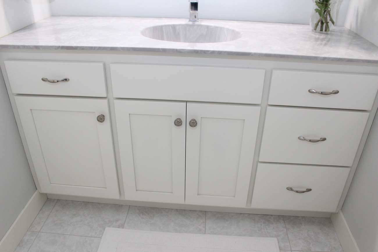 A bathroom vanity with white cabinets and drawers and a sink