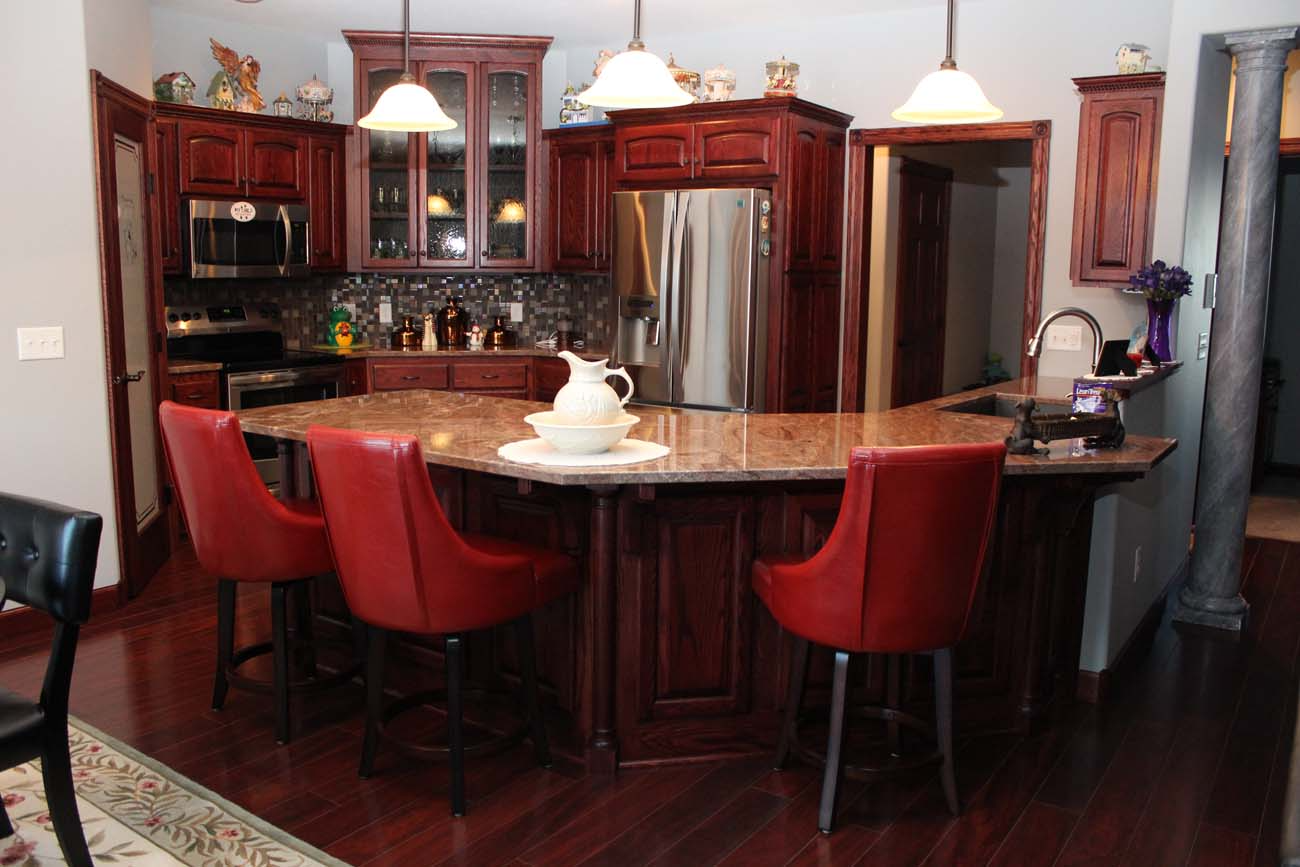 A kitchen with red chairs and a stainless steel refrigerator