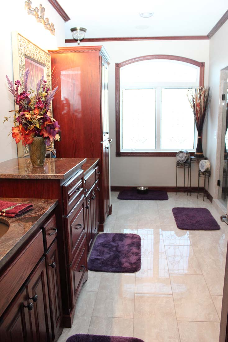 A bathroom with purple rugs and a vase of flowers
