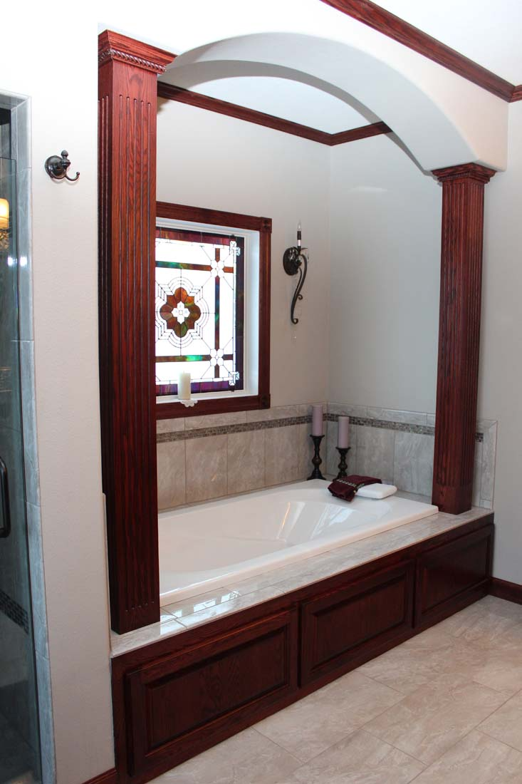A bathtub in a bathroom with a stained glass window
