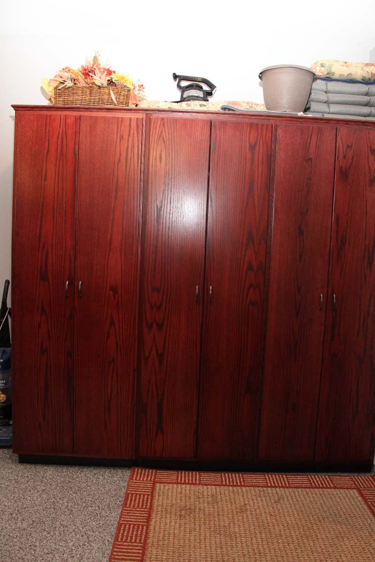 A large wooden cabinet is in a room next to a rug.