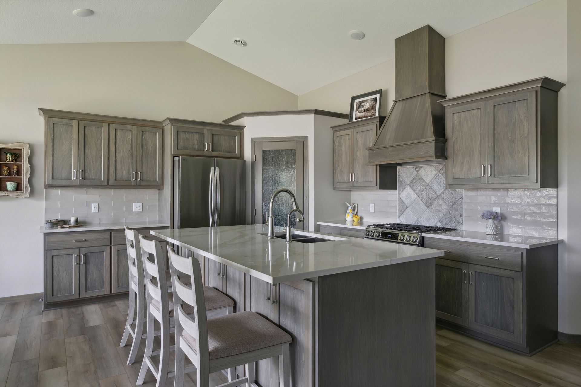 Modern kitchen with gray cabinets, island seating, and stainless steel range hood