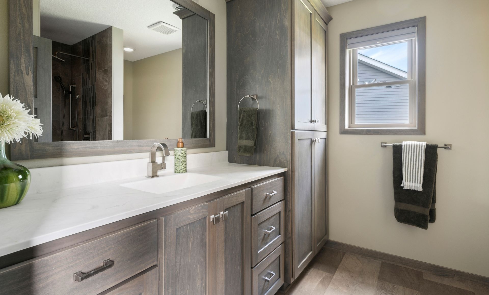 Modern bathroom vanity with double sinks, large mirror, wood cabinets, and a towel by the window