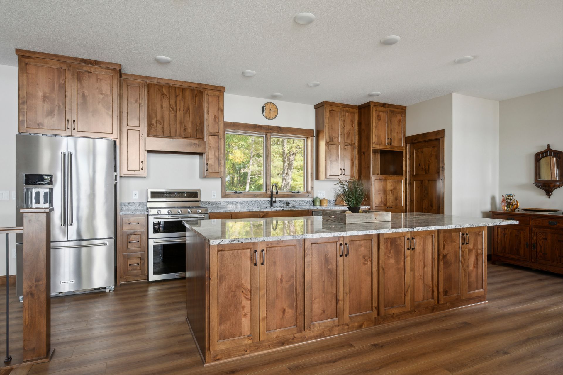 Bright kitchen with wooden cabinets, stainless steel appliances, and a large island under a window.
