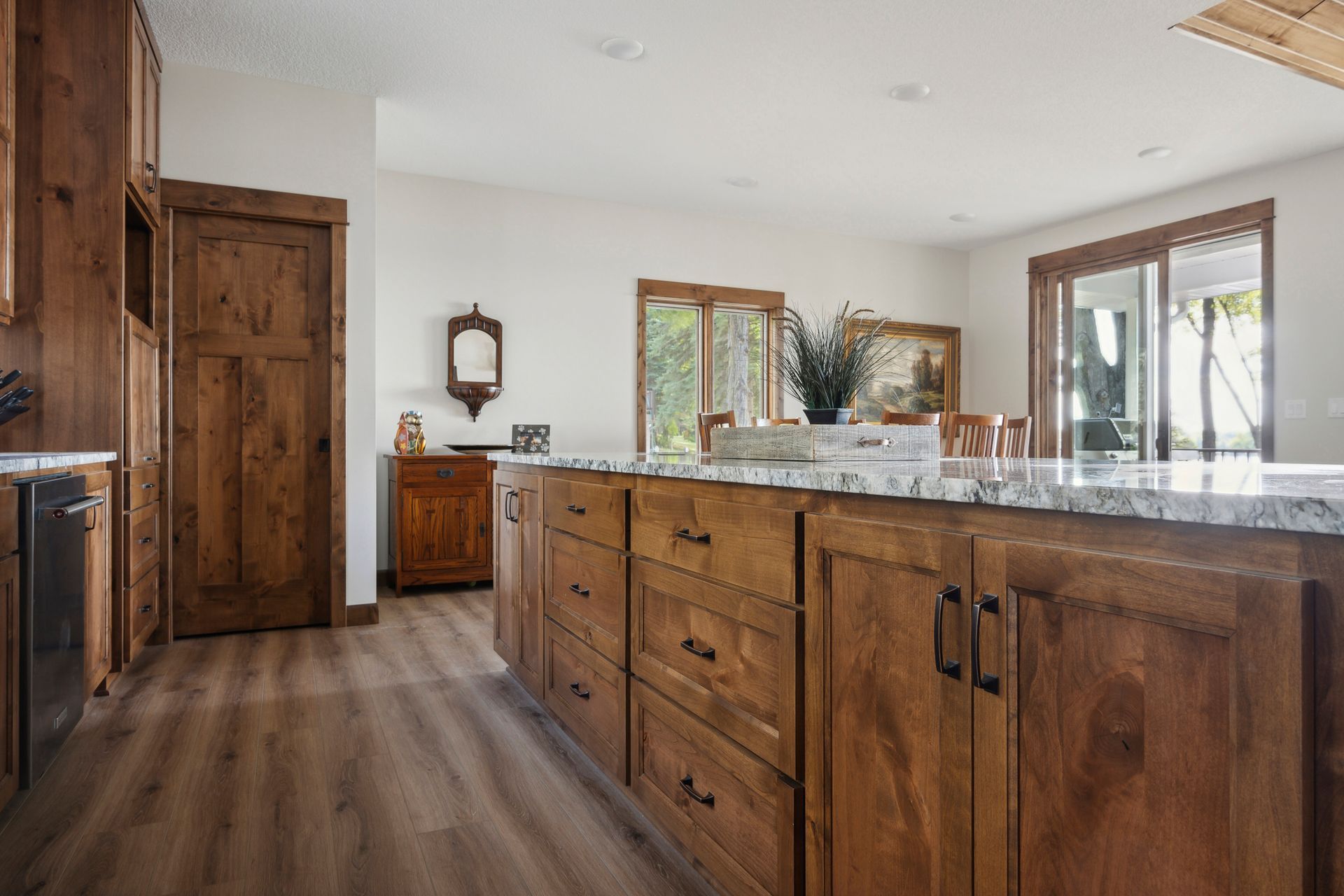 Spacious kitchen with wooden cabinets, granite island, and hardwood floors.