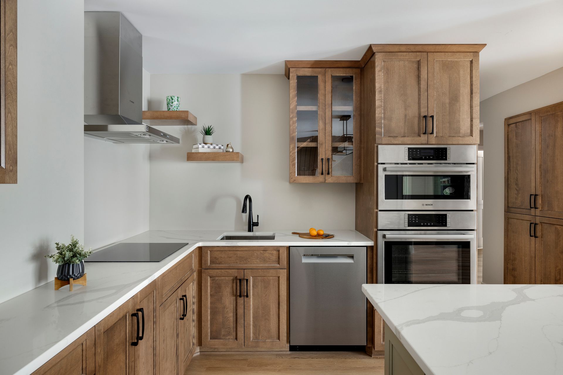 Modern kitchen with wood cabinets, white countertops, stainless appliances, and a small sink area